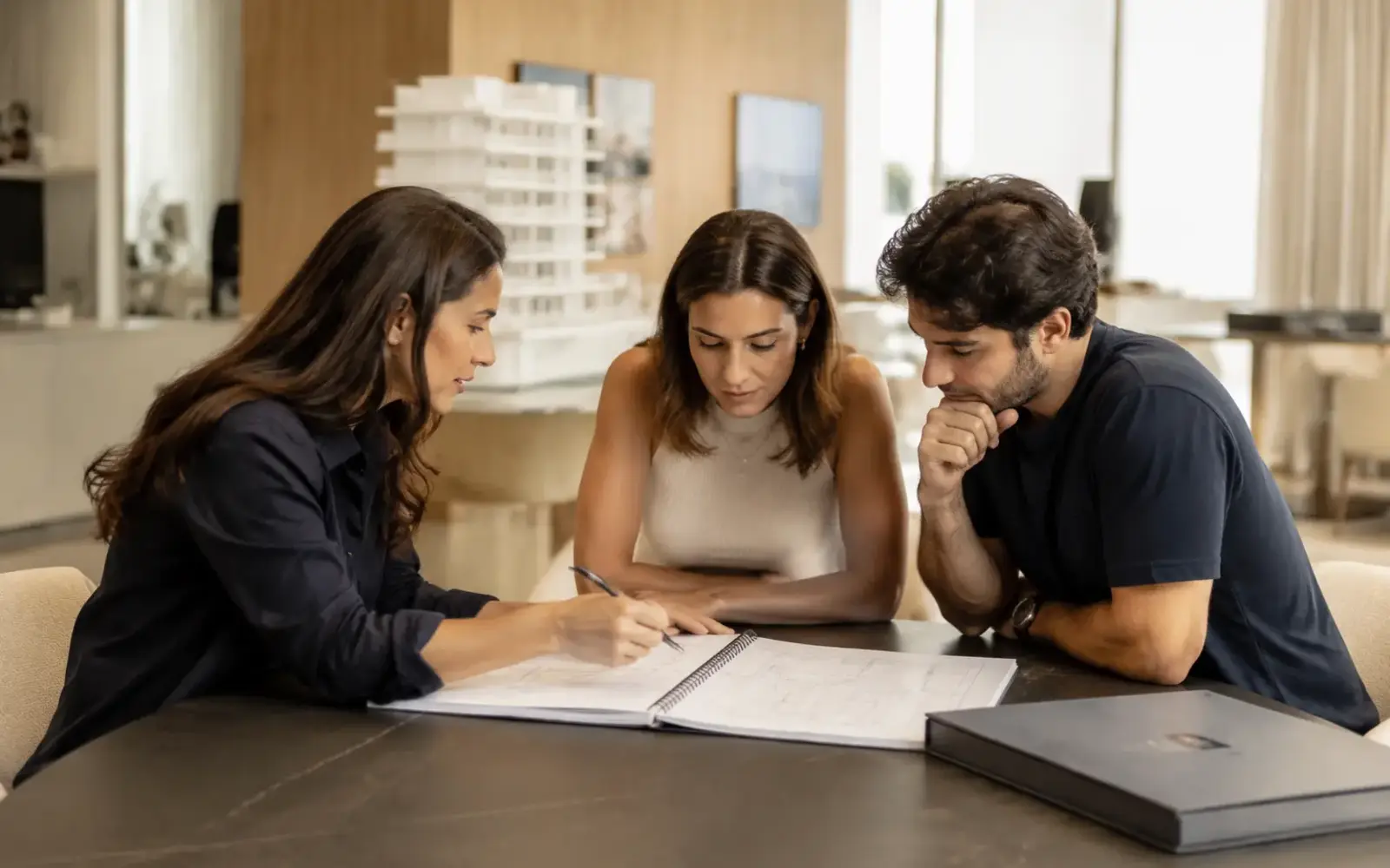 Casal analisando plantas impressas sobre uma mesa em estande de vendas